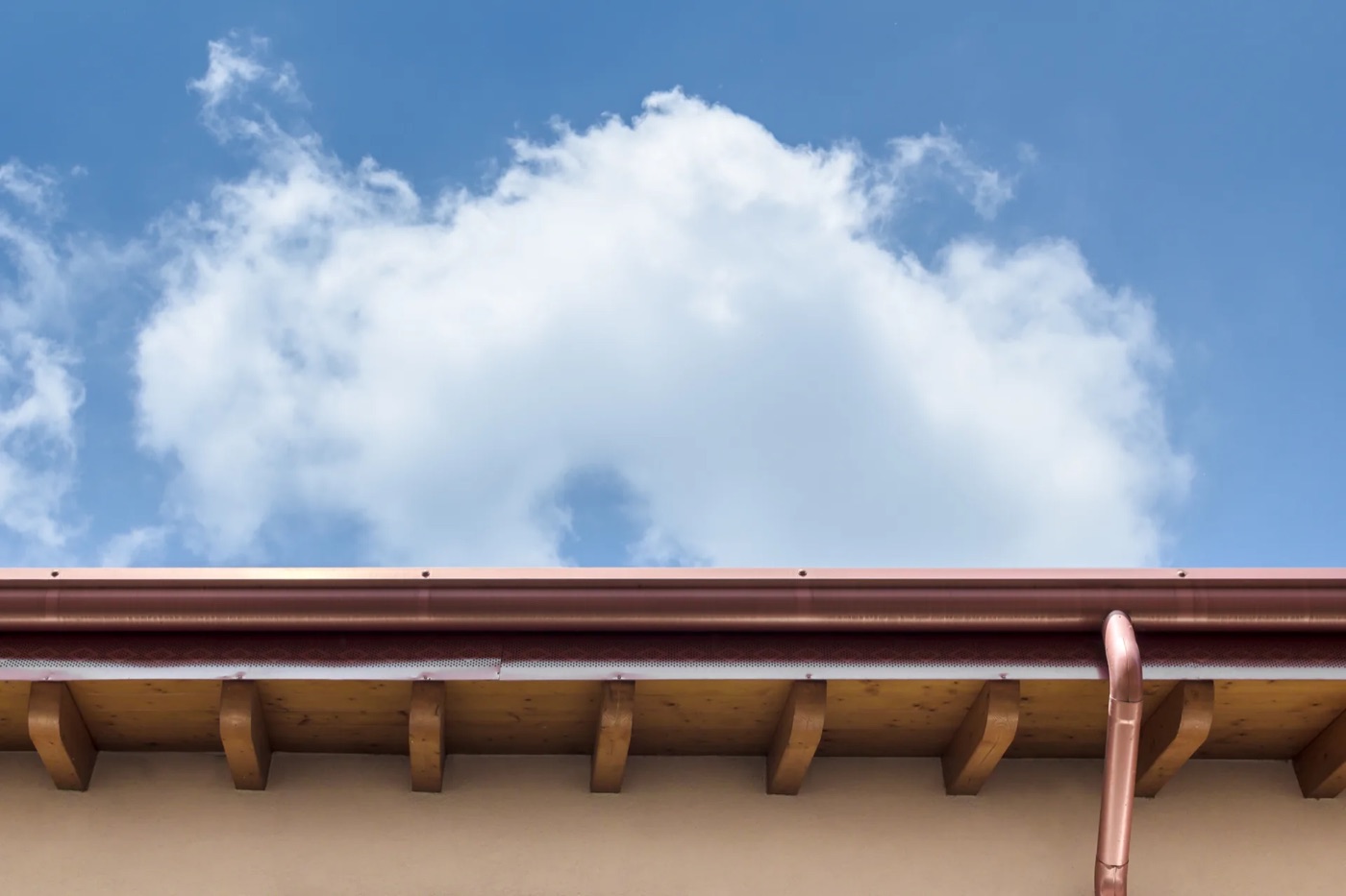 Copper gutter and round downspout installed along a roofline